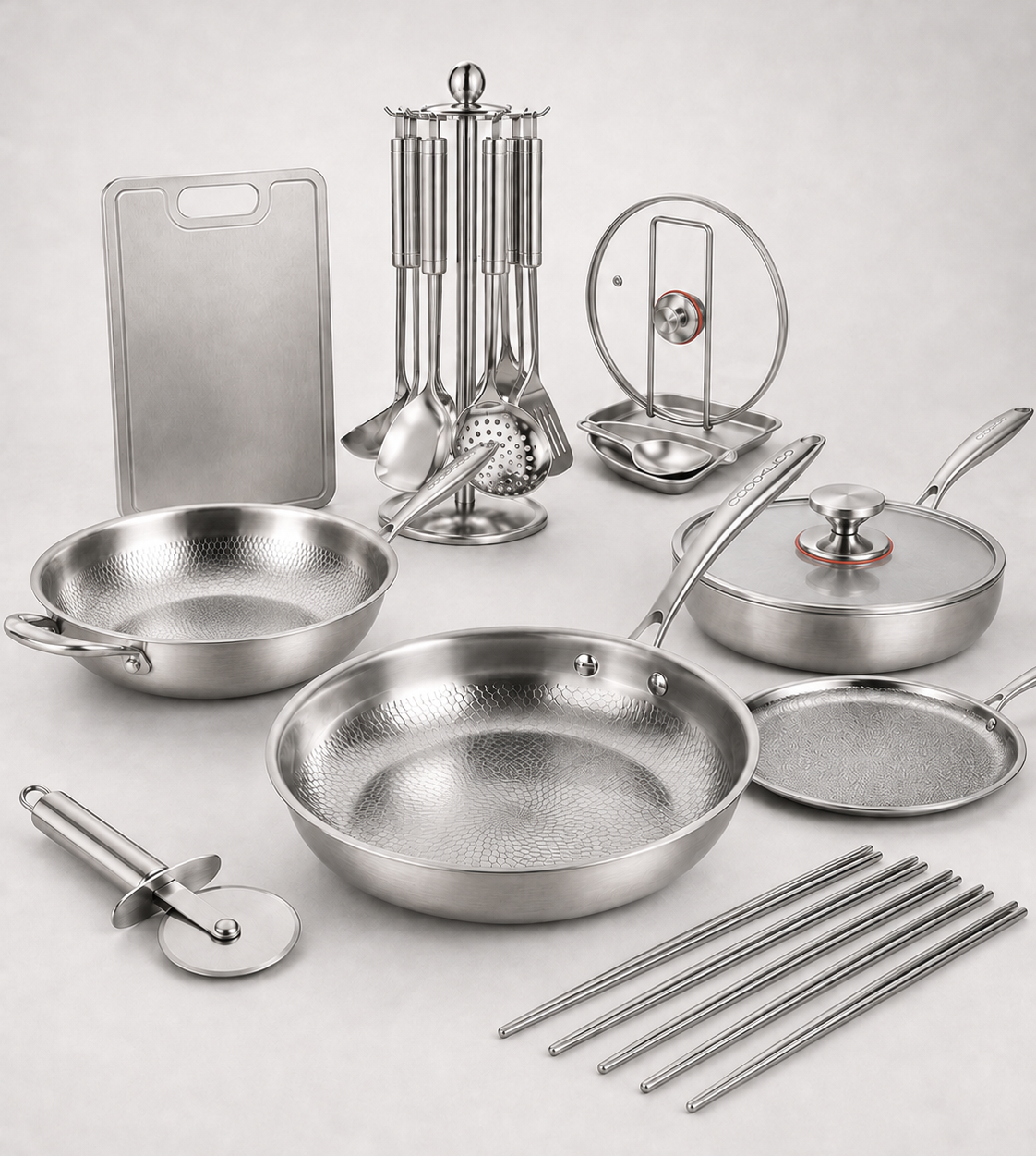 A stainless steel cookware set arranged on a light gray background, including frying pans, a pot with lid, cutting board, utensils, a strainer, a lid lifter, chopsticks, and a pizza cutter. The brand name Cooklico is printed at the top.